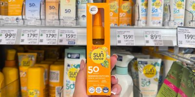 Ruka drží opalovací gel oproti regálu