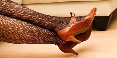 Ženské nohy v krajkovaných punčochách a kožených botách na podpatku