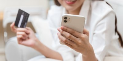 Žena drží v ruce kreditku a mobil