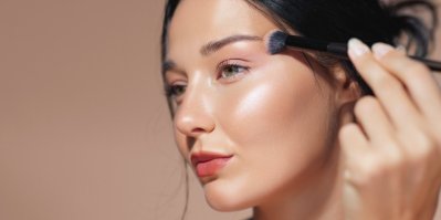 Mladá žena si štětcem nanáší make-up na obličej
