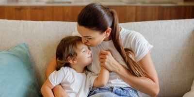 Žena dává synovi pusu a sedí na gauči