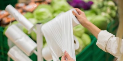 Žena vytahuje sáček z role v supermarketu