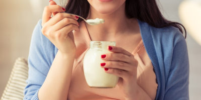 Žena jí bílý jogurt ze skleničky