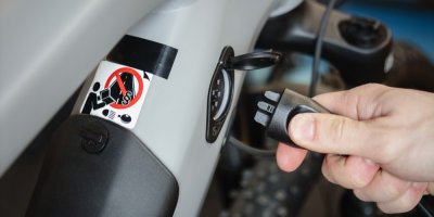 Člověk připojuje nabíjecí kabel k elektrokolu
