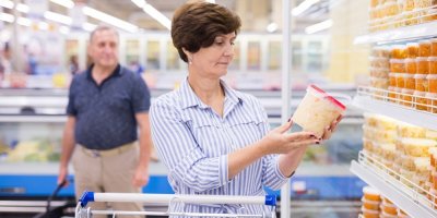 Starší žena si v supermarketu prohlíží balení kyselého zelí