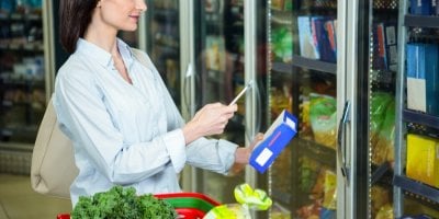 Žena si fotí na telefon produkt v supermarketu