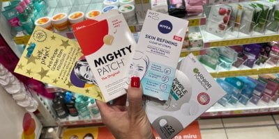 Ženská ruka drží v drogerii náplasti na pupínky v produktových obalech