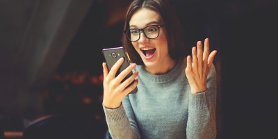 Žena se směje při pohledu na telefon
