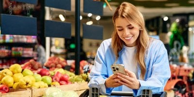 Usmívající se mladá žena nakupuje v supermarketu