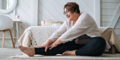 Žena středního věku se protahuje na koberečku v ložnici