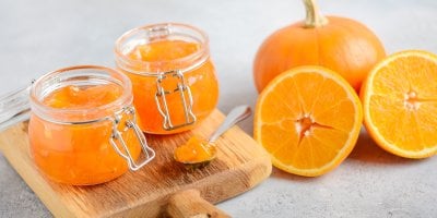 Oranžový džem ve sklenicích, vedle dýně a pomeranče