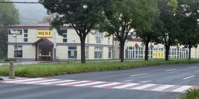 Budova obchodního řetězce Mere a protější silnice a řada stromů