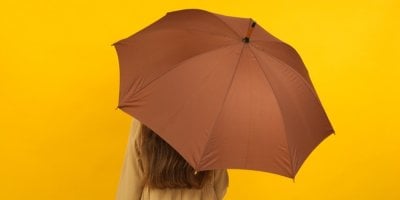 Dívka s hnědým deštníkem na žlutém pozadí