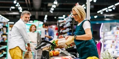 Pokladní markuje zákazníkovi nákup u pokladny v obchodě s potravinami