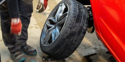 Muž mění v servisu kolo automobilu