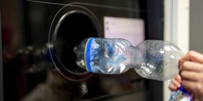 Žena vrací plastové lahve do recyklačního stroje