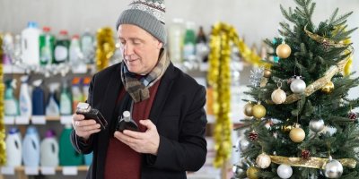 Starší zákazník si v obchodě vedle vánočního stromku vybírá parfém