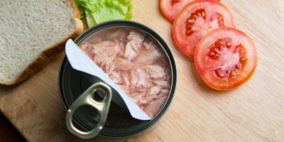 Otevřená tuňáková konzerva s nakrájenými rajčaty, chlebem a salátem