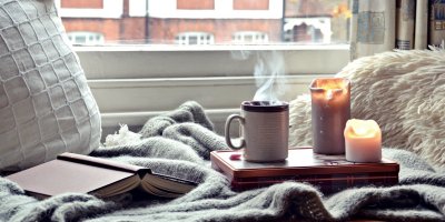 Posezení u okna s knihou, svíčkou a šálkem čaje