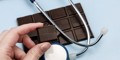 Kostička čokolády v rukou, pod ní stetoskop