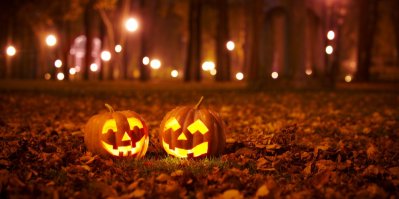 Dvě Halloweenské dýně s vydlabaným obličejem a svíčkou v osvětelném parku