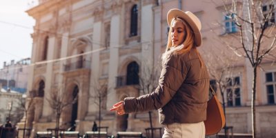 Mladá žena v jarní bundě před městskou budovou