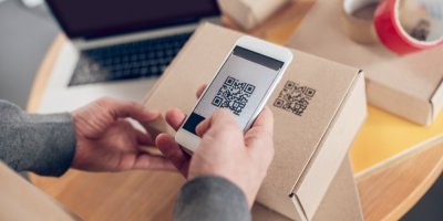 Muž mobilem skenuje QR kód na papírové krabici