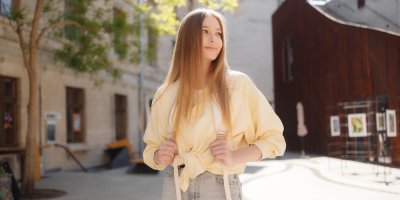 Mladá žena v máslově žluté košili v městském prostředí