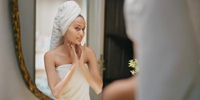 Mladá žena pečuje o svou pleť před zrcadlem