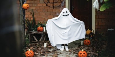 Halloweenský kostým ducha na verandě mezi halloweenskými dýněmi