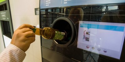 Žena vkládá vratnou lahev do automatu