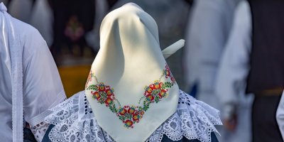 Žena v kroji a šátku zezadu