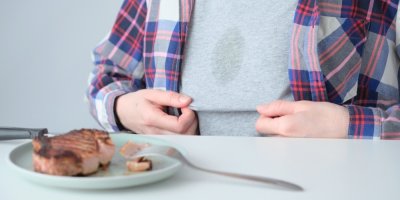 Člověk s mastnou skvrnou na tričku sedí u stolu