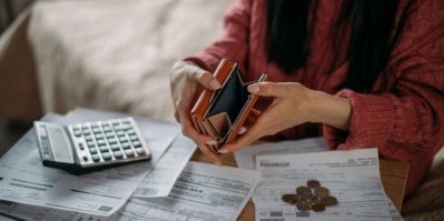 Žena s otevřenou peněženkou, kalkulačkou a účty na stole