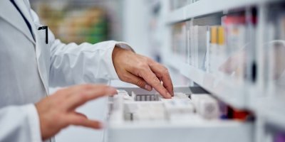 Ruce lékárníka hledají lék v šuplíku