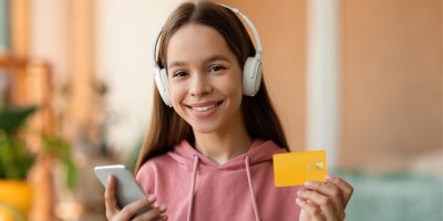 Dívka se sluchátky a mobilem a platební kartou v rukou