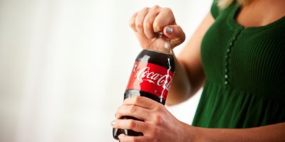 Žena otevírá láhev Coca-Coly