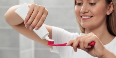 Žena si dává zubní pasu na kartáček