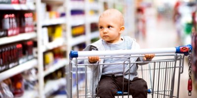 Malý kluk sedí v košíku v supermarketu