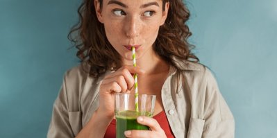 Žena pije zelené smoothie z pohárku