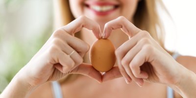 Žena drží rukama ve tvaru srdce vajíčko