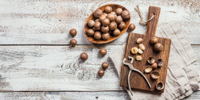 Makadamiové ořechy v misce a na prkénku, louskáček, utěrka