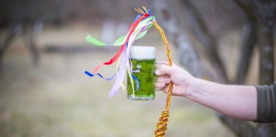 Ruka drží pomlázku a zelené pivo