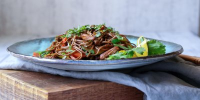 Soba nudle s kuřecím masem a zeleninou na modrém talířku