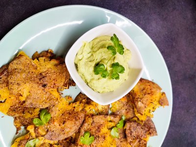 Upečené brambory s avokádovým dipem na bílém talíři