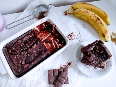 Fazolové brownies na talířku, vedle zapékací forma s brownies v pekáčku, banány a čokoláda