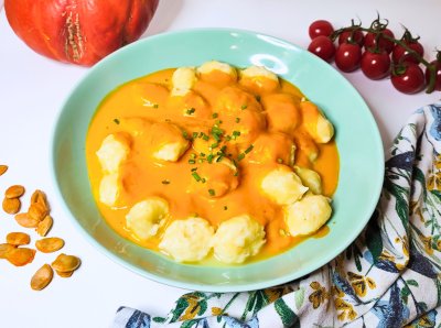 Noky s dýňovou omáčkou v hlubokém talíři, v pozadí dýně a cherry rajčata