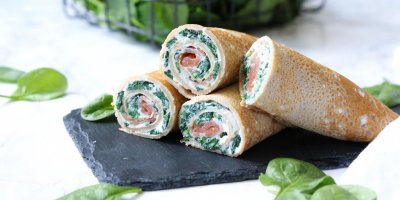 Pohankové palačinky se špenátem a uzeným lososem rozkrojené a naservírované na prkénku