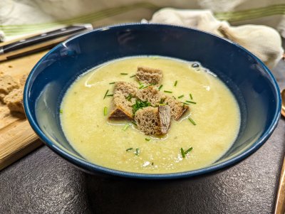 Krémová česnečka s krutonky a pažitkou, servírovaná v modrém talíři