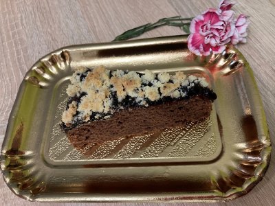 Kousek kakaového koláče s drobenkou na zlatém podtácku